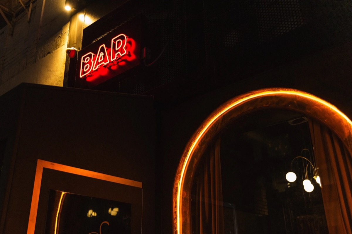 The neon BAR sign glowing at the entrance at night