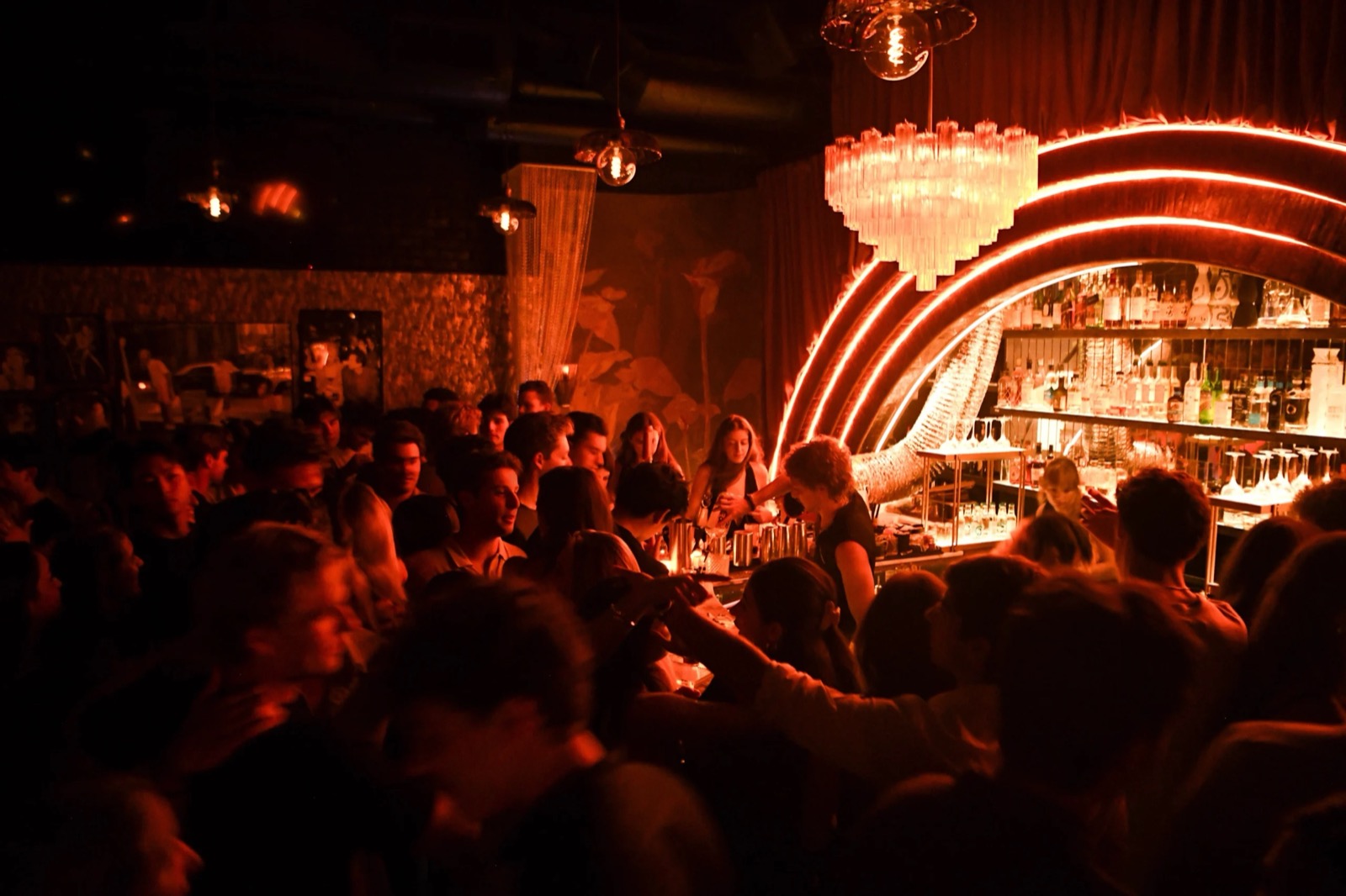 A packed night at Sweet Linda — the crowd at the bar while the team pours under the glowing arch